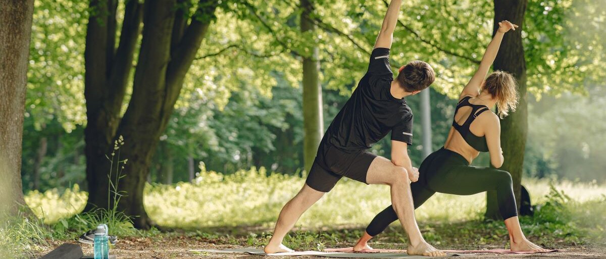  Junges, sportliches Paar macht Yoga, Fitness im Sommer im Park.