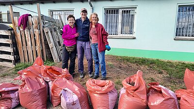 Im Vordergrund stehen mehrere befüllte Müllsäcke und im Hintergrund sind 3 Vereinsmitglieder zu sehen.
