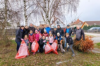 Das Foto zeigt mehrere Kinder und Erwachsene mit befüllten Müllsäcken und Greifzangen.
