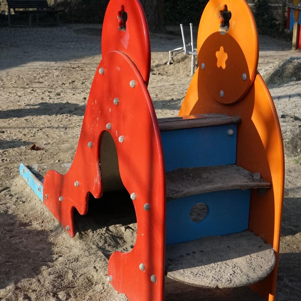 eine kleine Rutsche mit rot-orangen Gestell und blauen Stufen