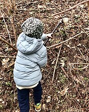 Ein Kind sammelt Müll mit einer Greifzange auf.