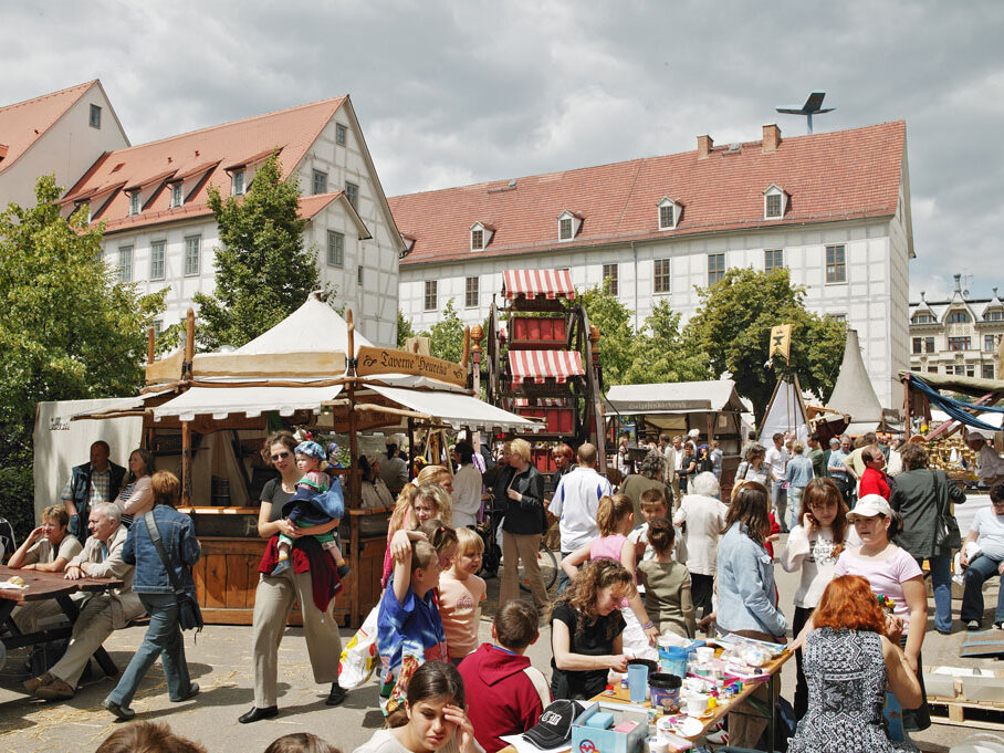 Besucher zwischen mittelalterlichen Marktständen im Außengelände der Franckeschen Stiftungen