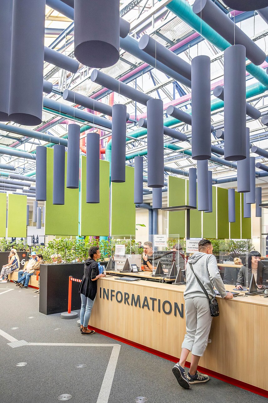 Mann und Frau im Gespräch jeweils mit Mitarbeitern der Stadtverwaltung am Tresen mit der Aufschrift „Information" im Bürgerservice der Stadt Halle. 