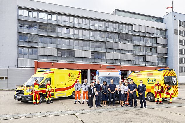 Gruppenfoto vor 3 Rettungswagen an der Leitstelle.