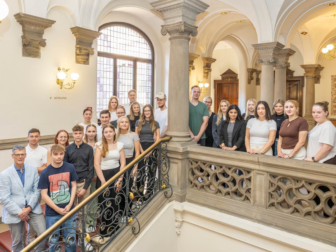 Die Gruppe steht auf der Treppe im Flur des Stadthauses.