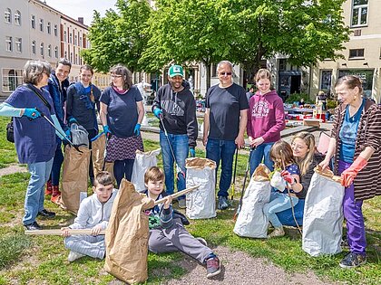 Gruppenfoto von teilnehmenden Anwohnern und Vereinsmitgliedern der Müllsammelaktion vor dem Brunnen am August-Bebel-Platz