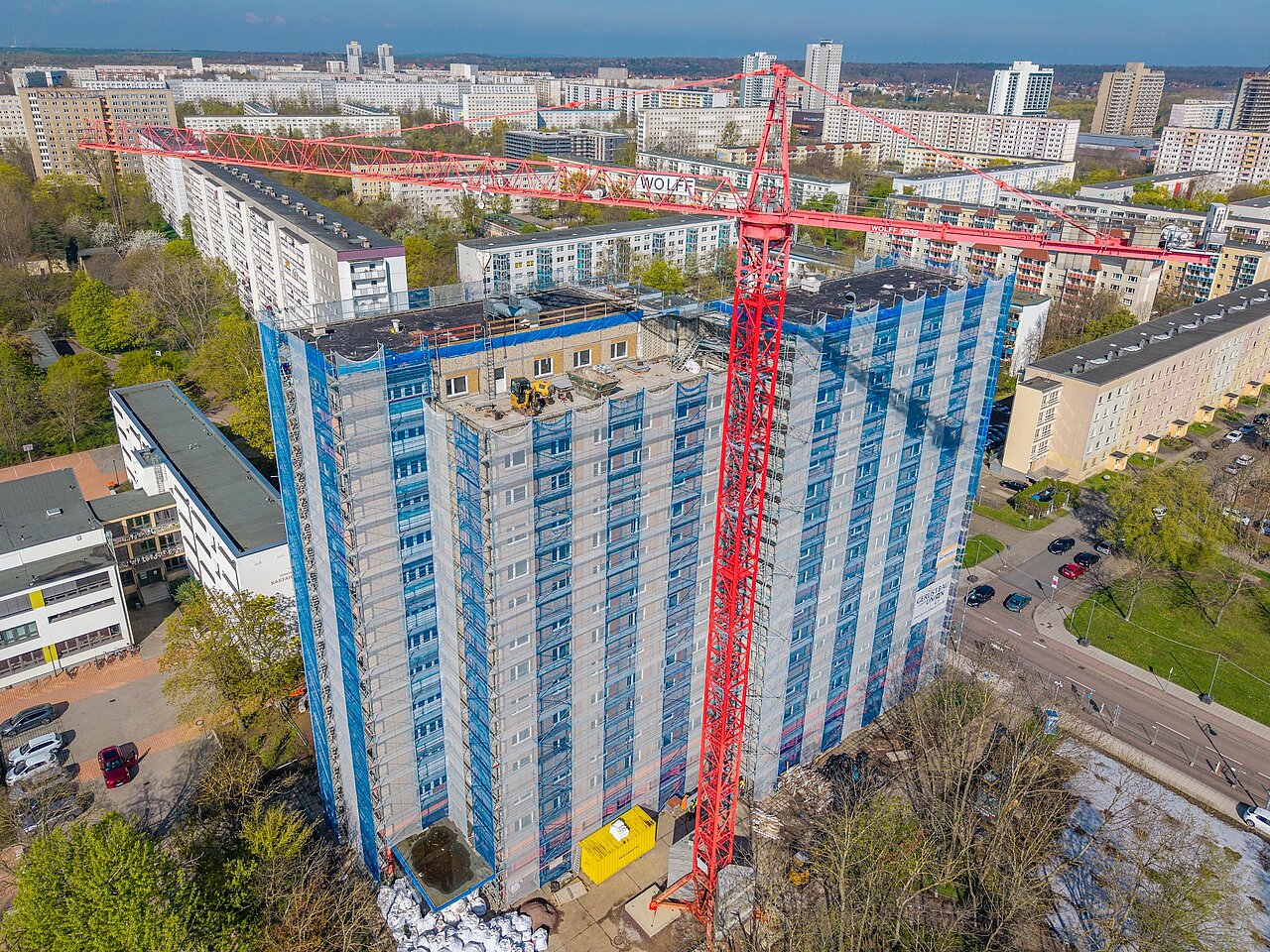 Ein Baukran vor dem eingerüsteten Hochhaus. 