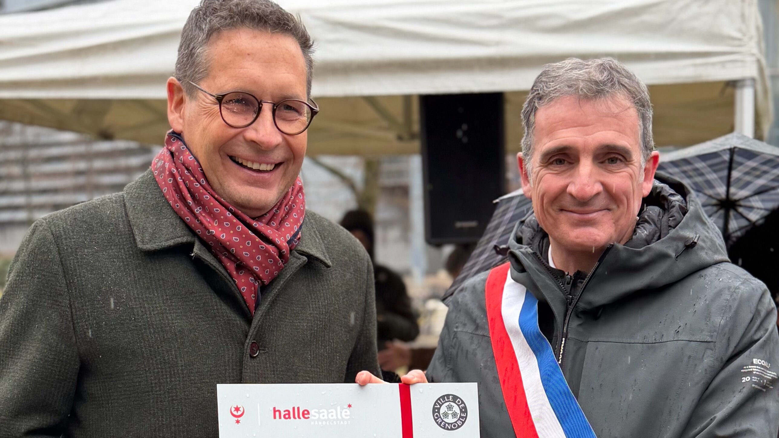 Oberbürgermeister Dr. Alexander Vogt und Bürgermeister Éric Piolle halten ein Schild in der Hand, für die Einweihung des „Square de Halle-sur-Saale“
