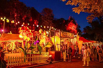 Zauberhafte Welt aus beleuchteten Blumen, Lampions und Zirkuswagen