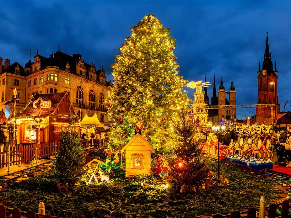 Weihnachtssbaum in Abendstimmung, davor Kindereisenbahn