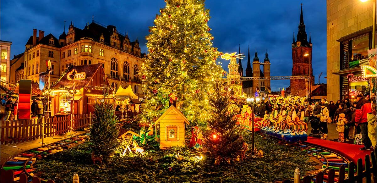 Weihnachtssbaum in Abendstimmung, davor Kindereisenbahn