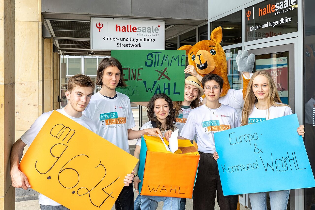 6 junge Menschen werben mit bunten Schildern für eine Wahlteilnahme.