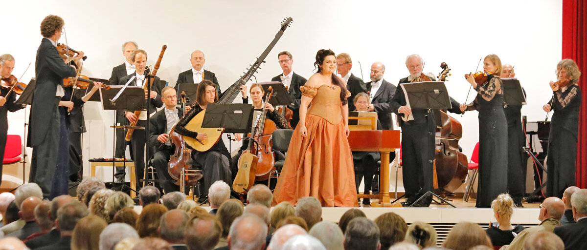 Musiker und Musikerinnen mit teilweise historischen Instrumenten, im Vordergrund Kammersängerin Romelia Lichtenstein 