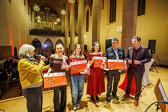 Übergabe der Ehrenamtskarte 2026 an Ehrenamtliche auf der Bühne, Frau Leonhardt spricht am Mikrofon.