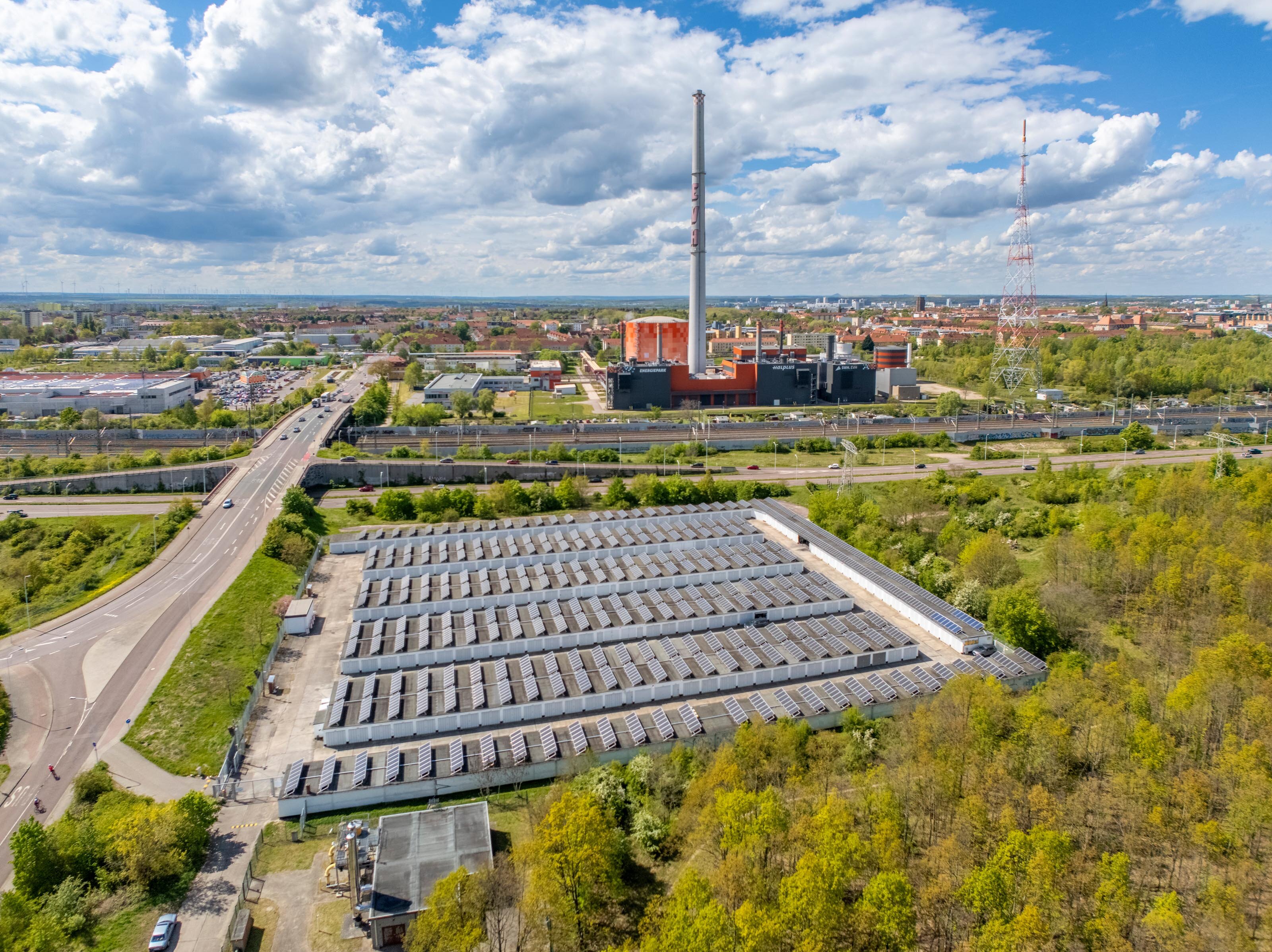 Das Bild zeigt eine Luftaufnahme der Dieselstraße in Halle. Die Straße bildet sich links am Bildrand ab. Zentral im Bild ist ein Garagenkomplex mit Solaranlagen zu erkenn. Am Horizont befindet sich der Schornstein vom Produktionsgelände der EVH und die ersten Häuserreihen der Stadt.