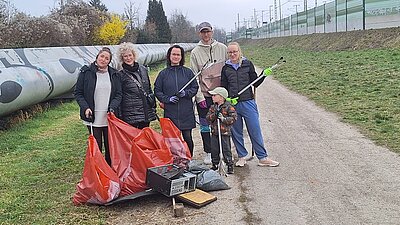 Auf dem Foto sind mehrere Personen zu sehen, die Müllsäcke und Greifzangen in den Händen halten.