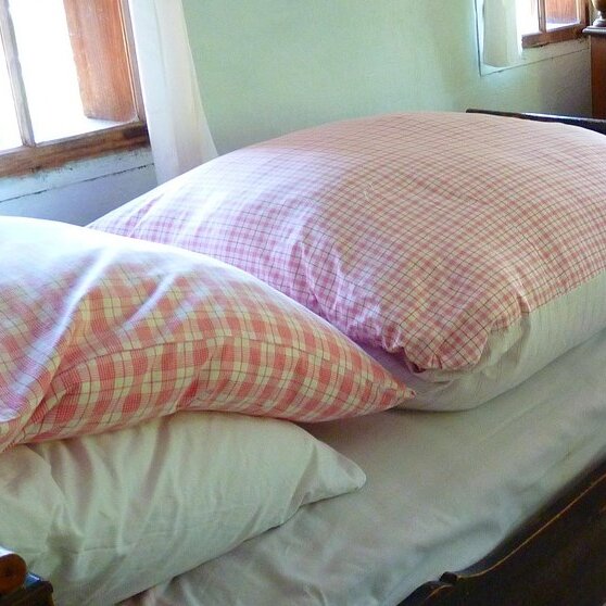 ein Bett mit einem Federkissen und einer Federdecke mit buntem Bezug