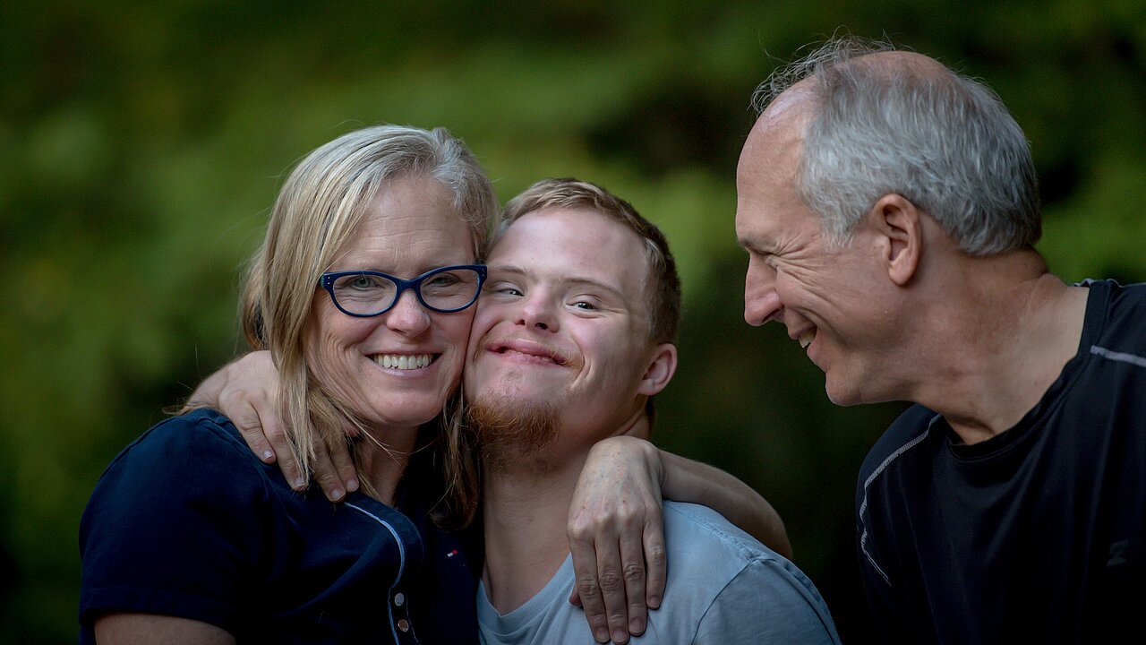 Eltern kuscheln und lachen mit ihrem Down-Syndrom-Kind