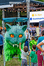ein Kind streichelt eine große grüne Katze - Requisite des Märchenballett-Stücks "Alice im Wunderland"
