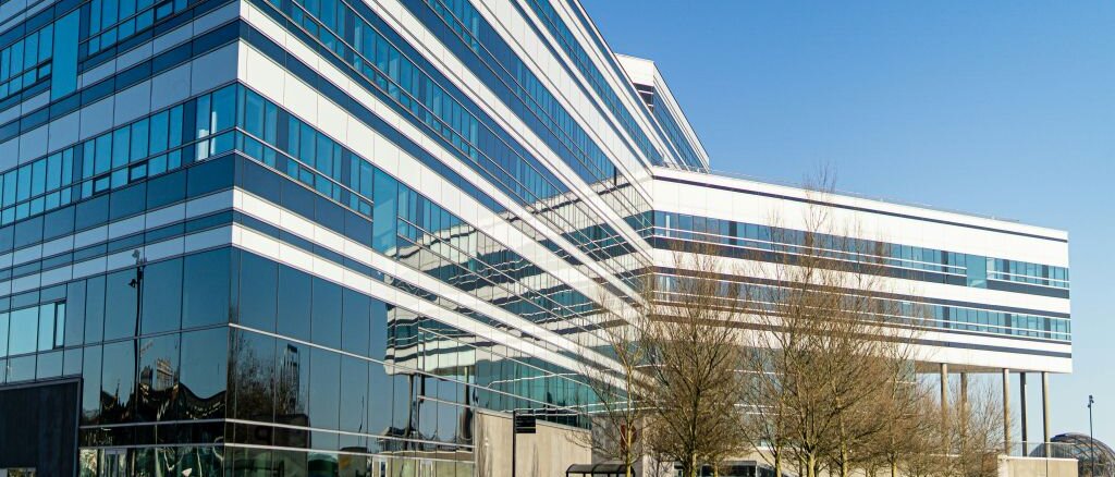 modernes Bürogebäude mit Glasfassade, im Vordergrund Bäume