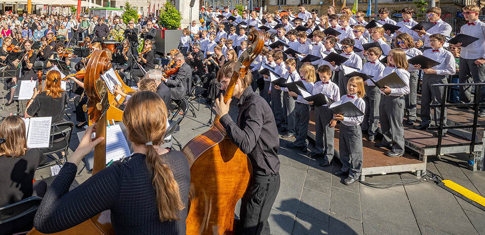 Orchester mit Dirigent und Chor spielen neben Händel-Denkmal auf dem Marktplatz