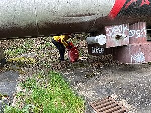 Ein Beteiligter schaut unter einem Heizrohr vor und hält einen Müllsack in der Hand.