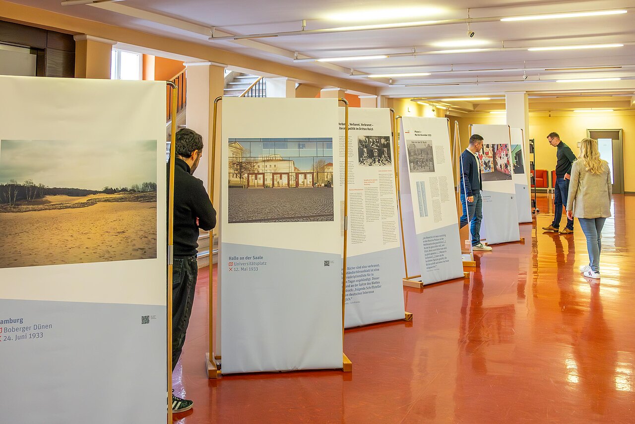 Menschen betrachten die Aufsteller der Ausstellung zu den Bücherverbrennungen von 1933 