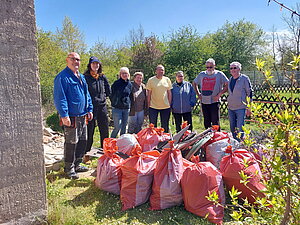 Gruppenbild mit den Beteiligten sowie befüllten Müllsäcken im Vordergrund.