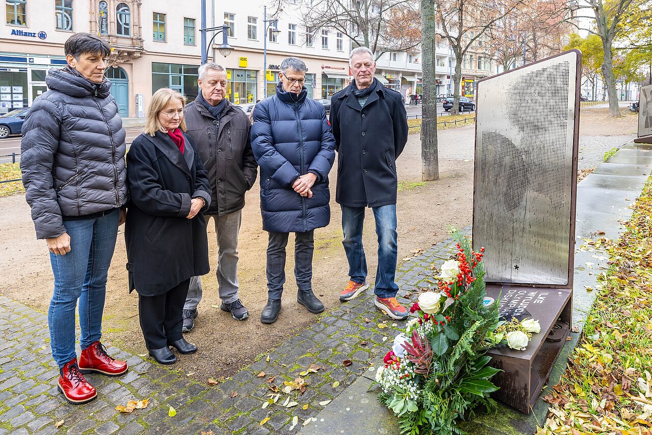 Zwei Frauen und drei Männer stehen an einer Stele, die das Bild der verstorbenen Olympiasiegerin Ilke Wyludda zeigt