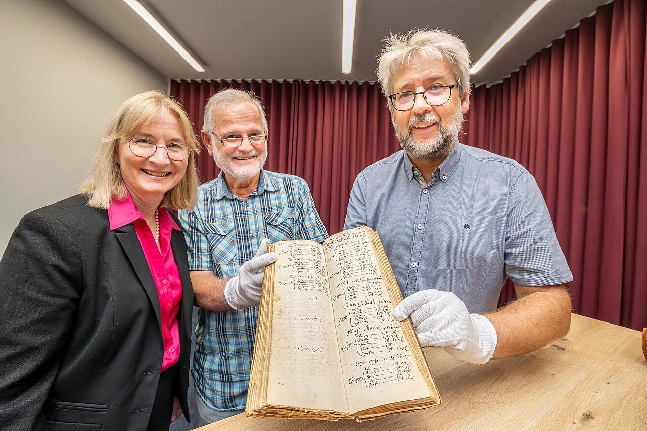 er ehemalige Eigentümer der 400 Jahre alten Handschrift, die Beigeordnete für Kultur und Sport, Dr. Judith Marquardt, und der Leiter des Stadtarchivs Halle, Ralf Jacob mit der wertvollen Handschrift 