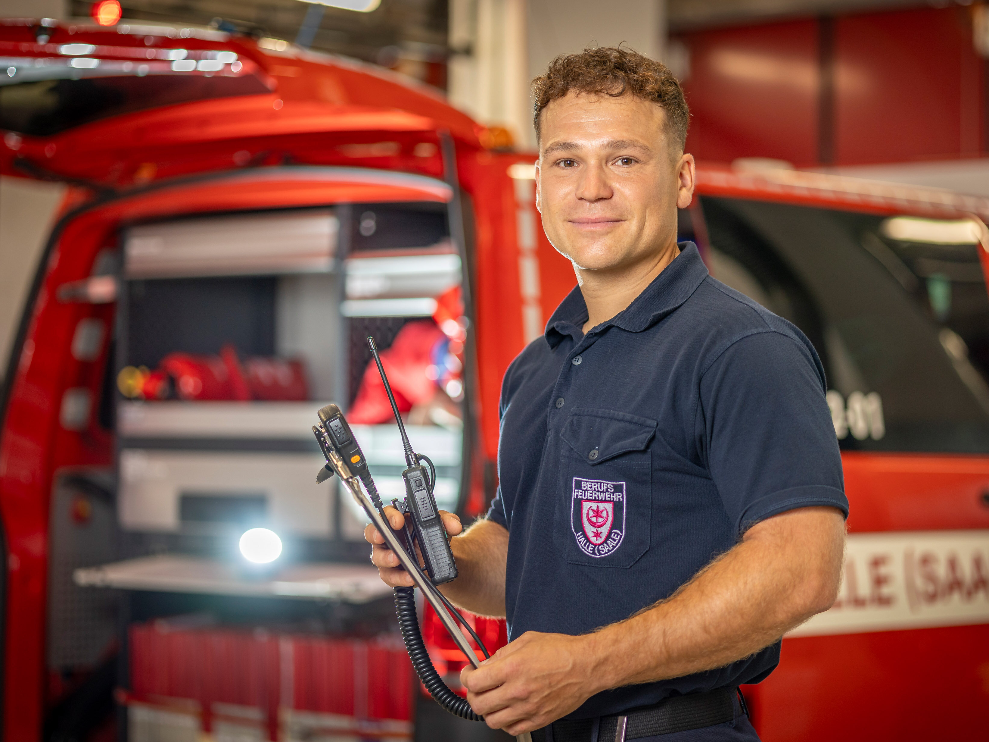 Thomas Günther, Oberbrandmeister bei der Berufsfeuerwehr Halle (Saael), vor seinem Einsatzfahrzeug mit einem Klemmbrett in der Hand