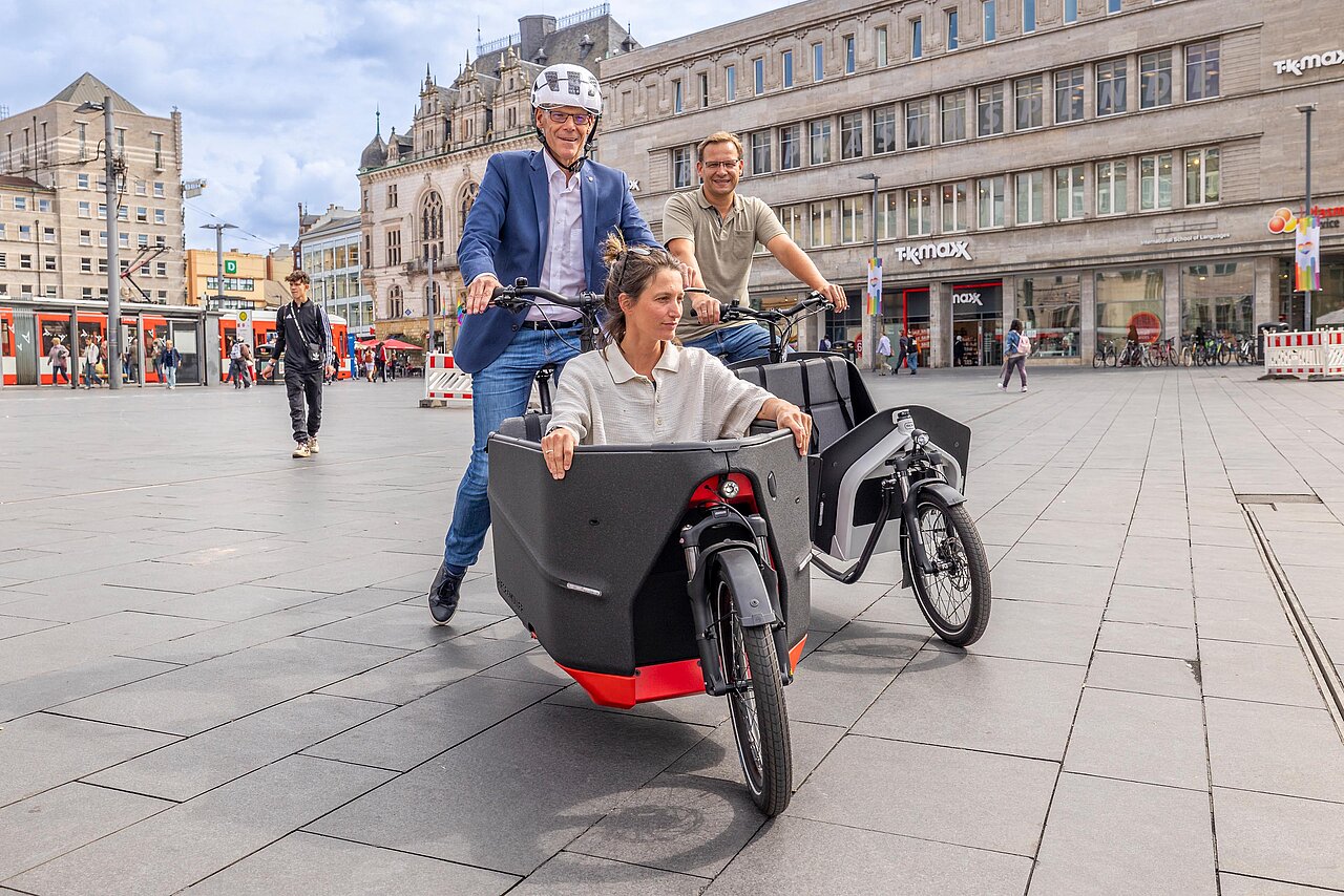 Der Bürgermeister fährt ein Lastenrad, vorne sitzt eine Person im Rad.