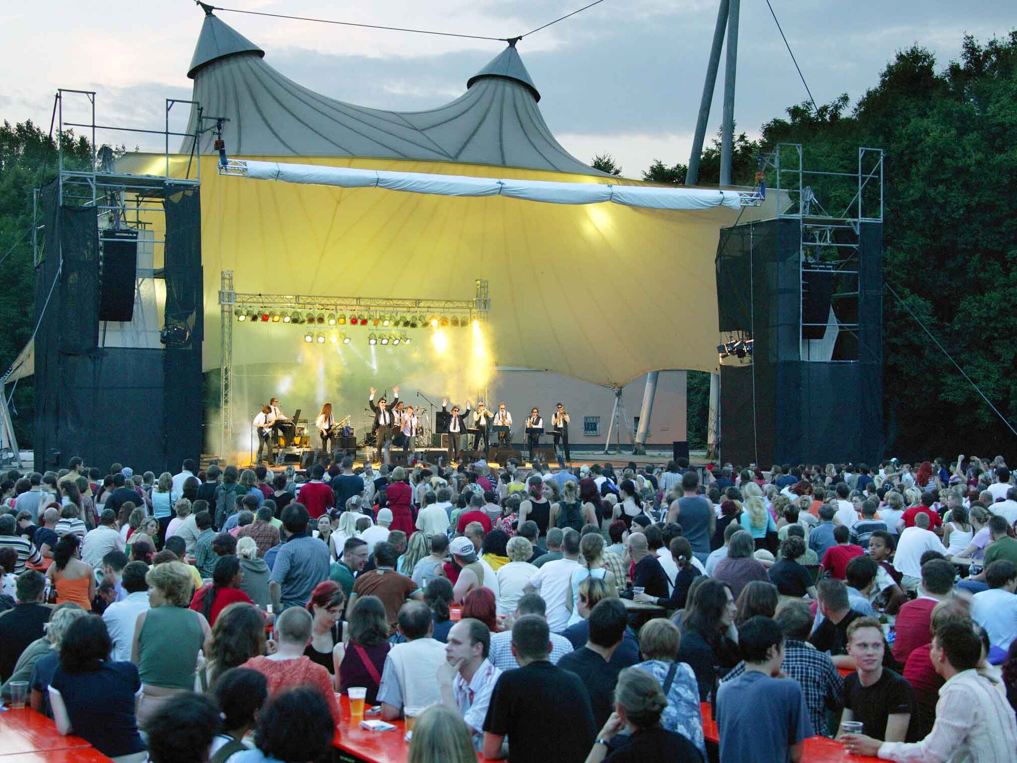 Mehrere Zuschauer sitzen vor der Bühne und schauen sich ein Konzert eines Künstlers an