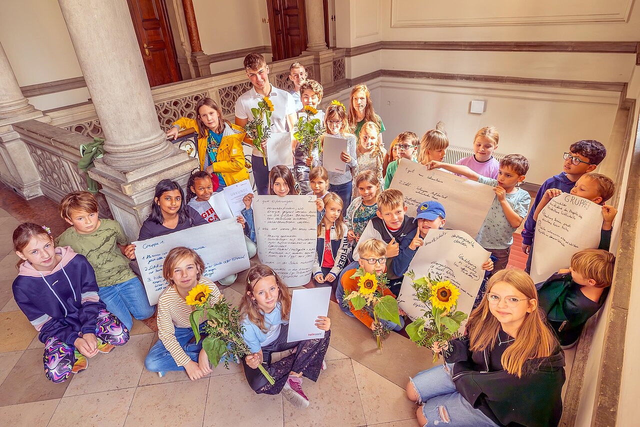 Die Schülerinnen und Schüler stehen im Flur des Stadthauses mit Urkunden und Blumen.