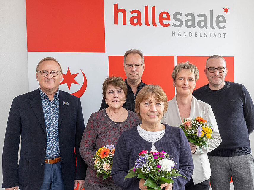 3 Männer und 3 Frauen vor dem Logo der Stadt Halle (Saale)